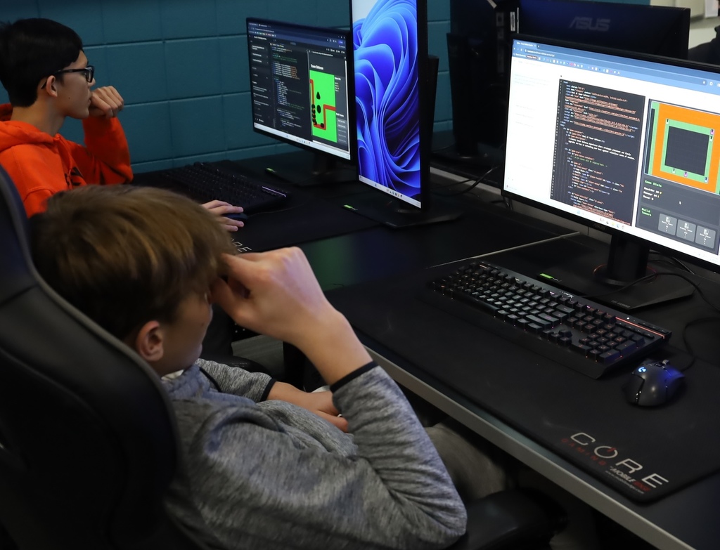 Two students coding and playing games on their computer
