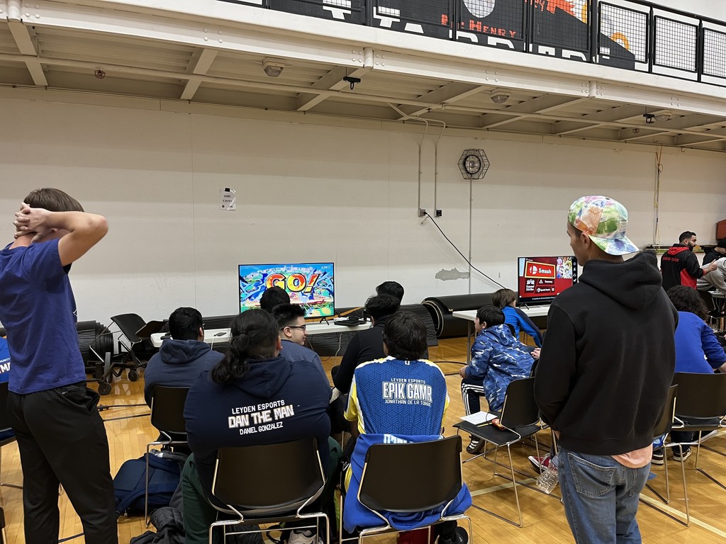 Students gathered around a computer playing a video game 