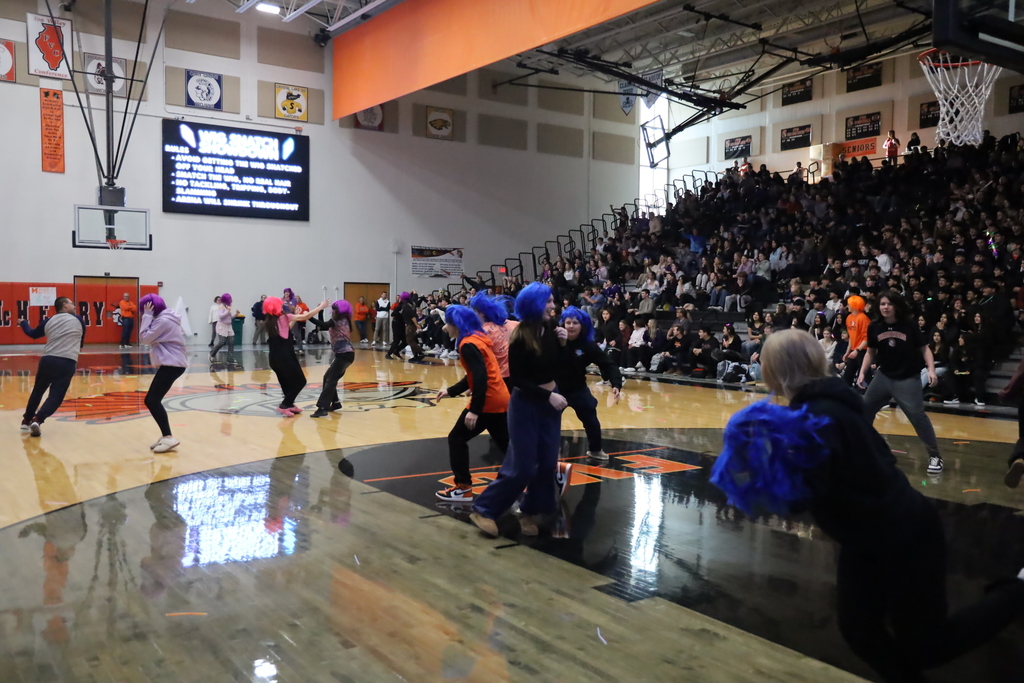Students running with colorful wigs in the gym 