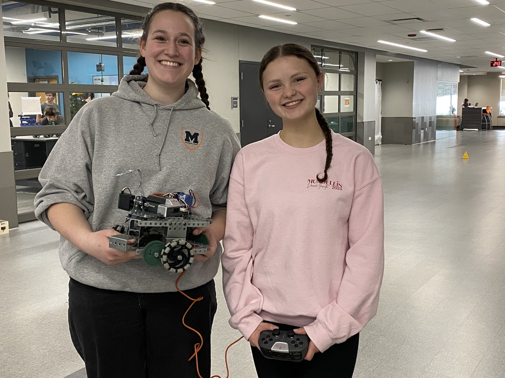 Two students, one holding a robot and the other one holding a remote control 