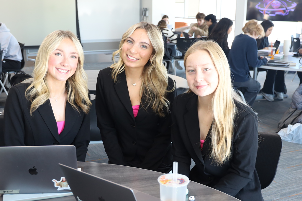 Three students at  table wearing matching business outfits