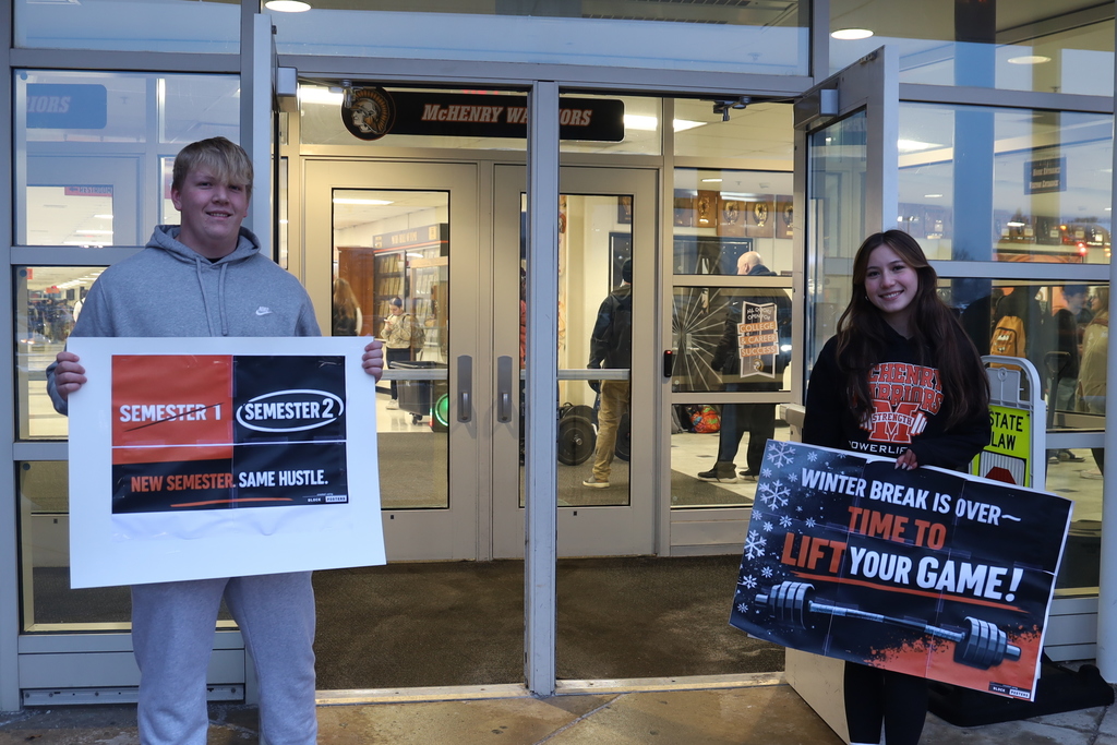 Two Students holding signs" Semester one crossed out Semester 2 New semester same hustle" Winter Break is over time to lift your game"