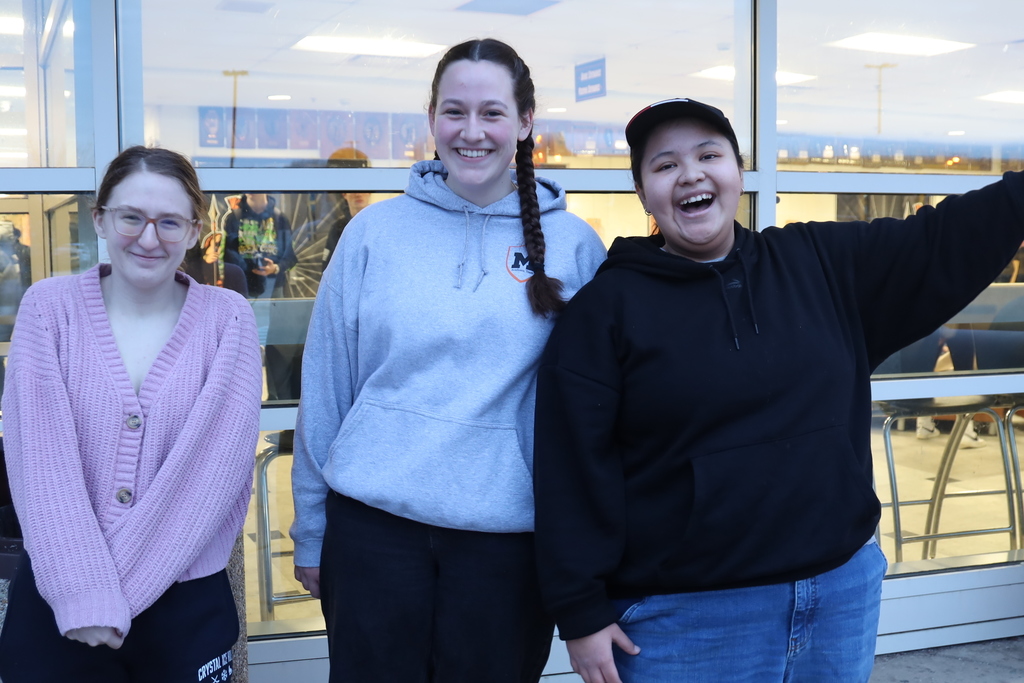 Three students smiling at the front entrance