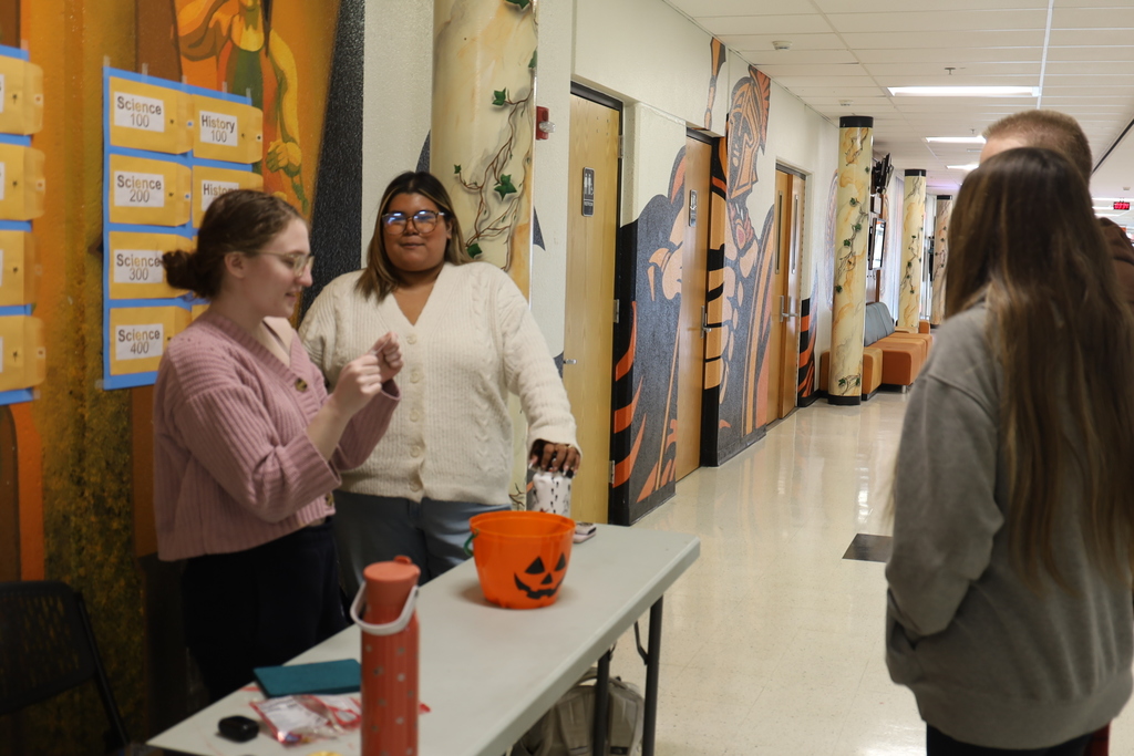 Student at booth asking a trivia question to two other students