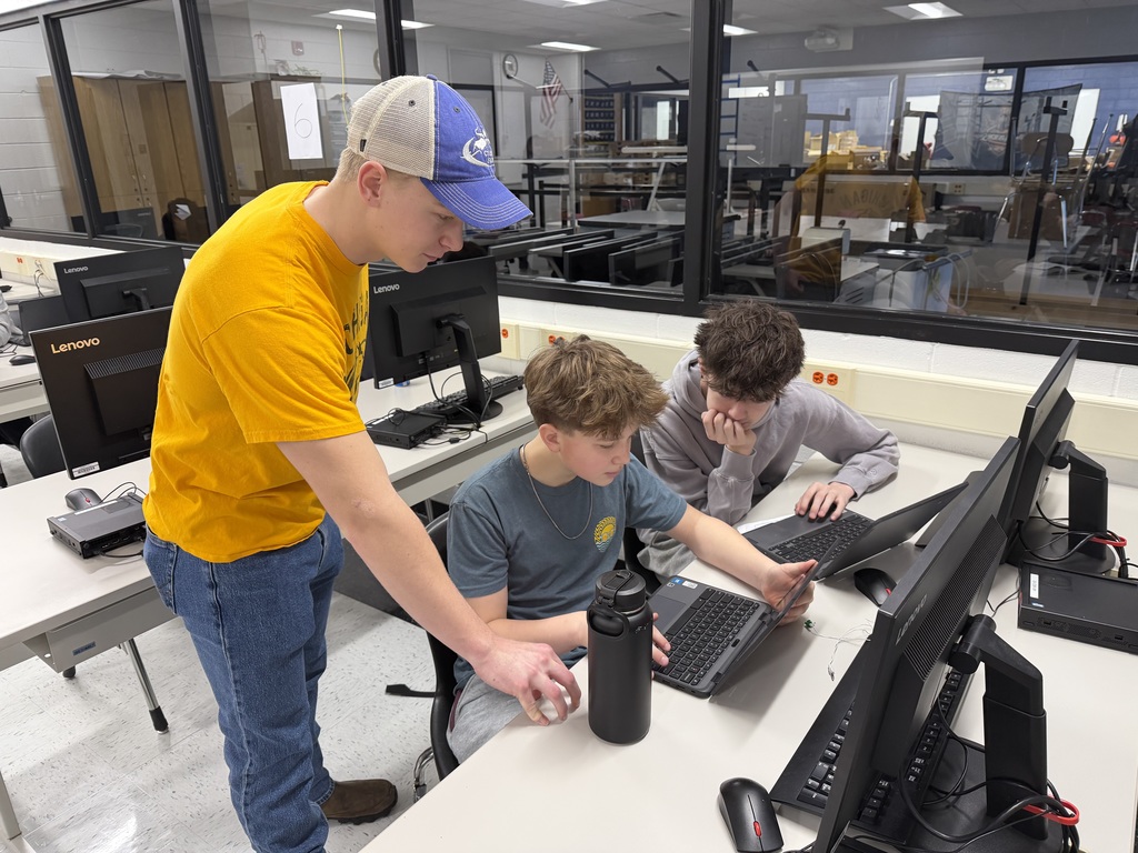 Student helping two students on the computer