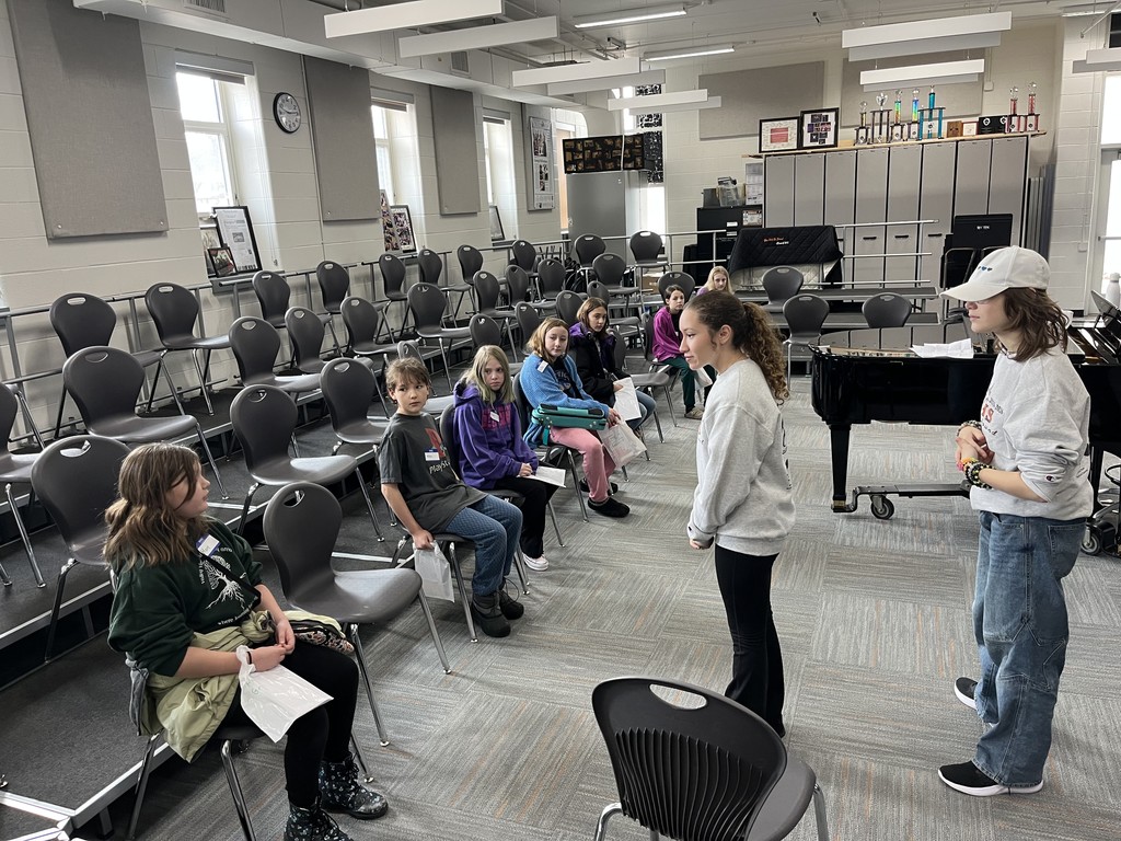 Younger students sitting with two high school students leading