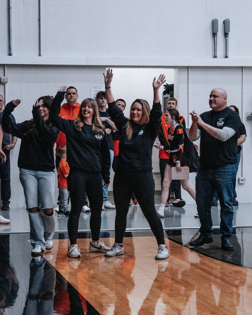 Riverside owners and/or staff standing on the gym floor  waving with superintendent  