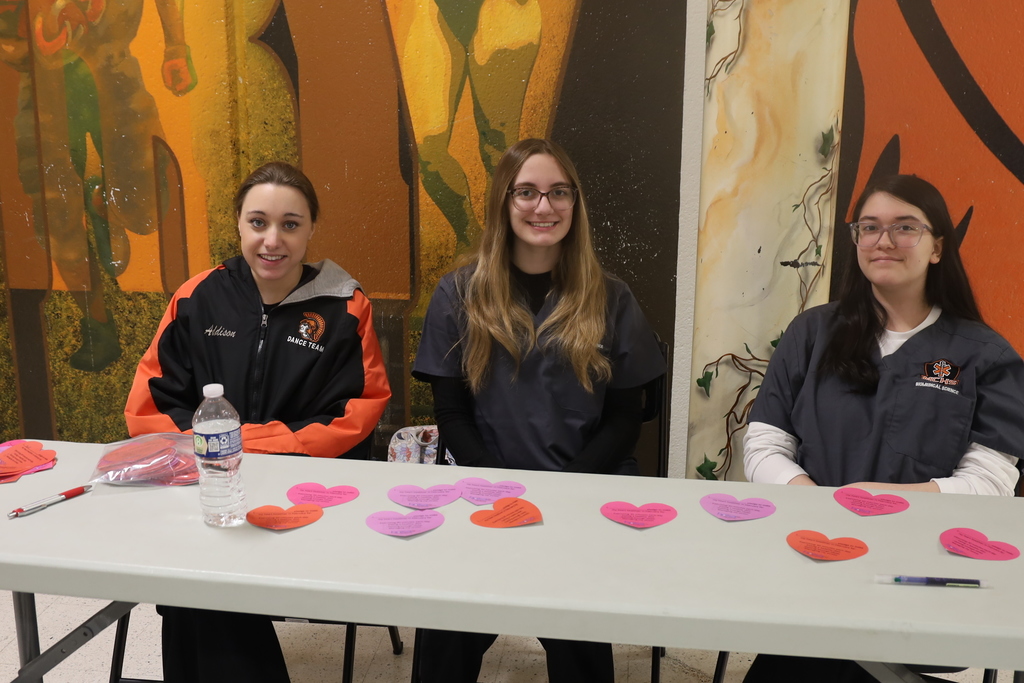 Three students at a table with paper hearts 