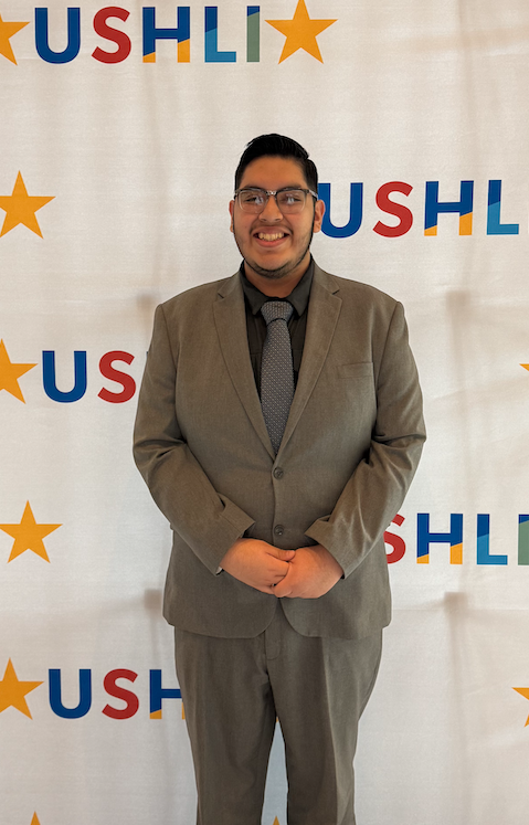 Student standing in front of USHLI poster