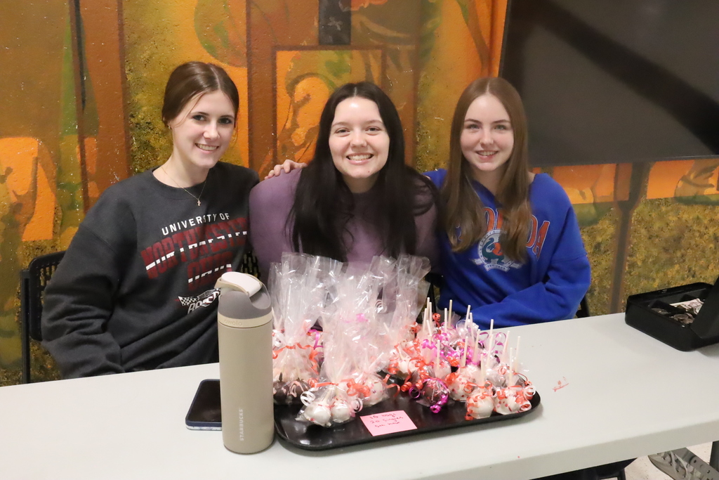 Three students selling Valentine's Day cake pops.