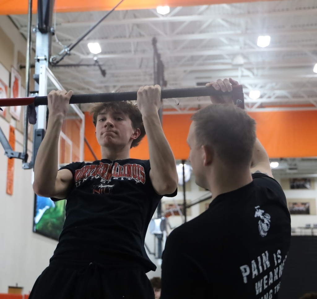 Student doing pull-ups next to a marine