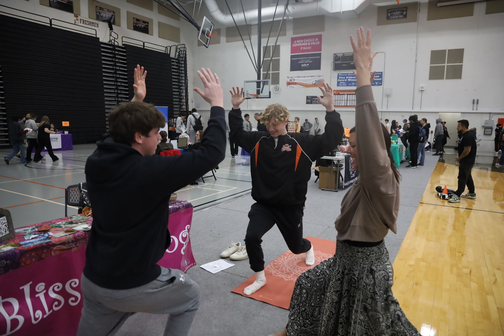 Two students doing yoga with a yoga instructor