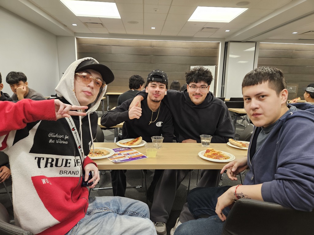 Students at a table eating pizza
