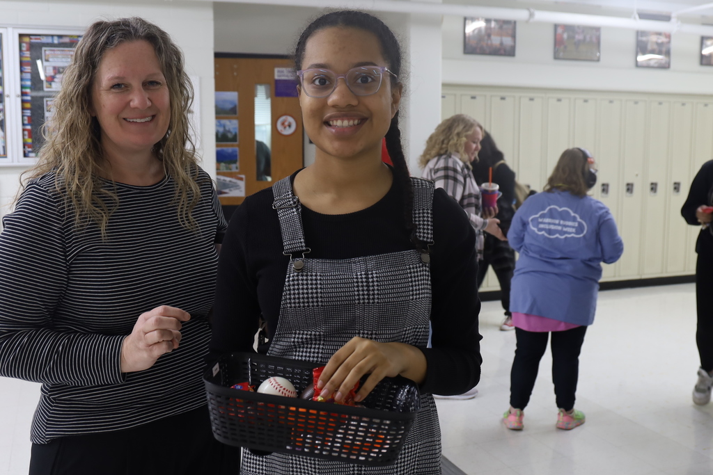 Staff member and student holding goodies basket
