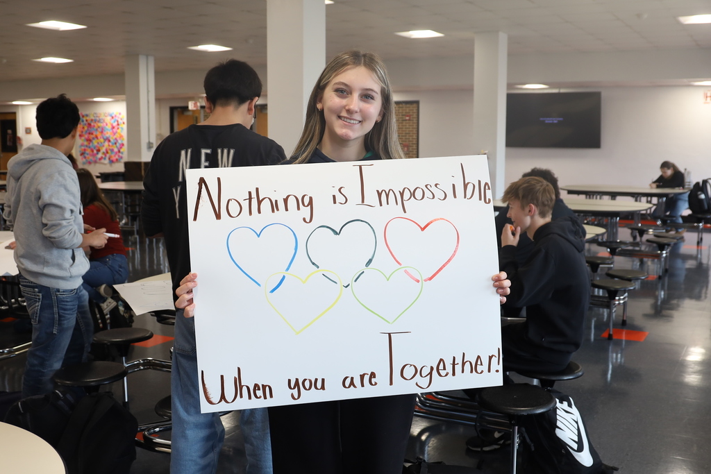 Student holding up poster that says Nothing is Impossible When you are together with hearts