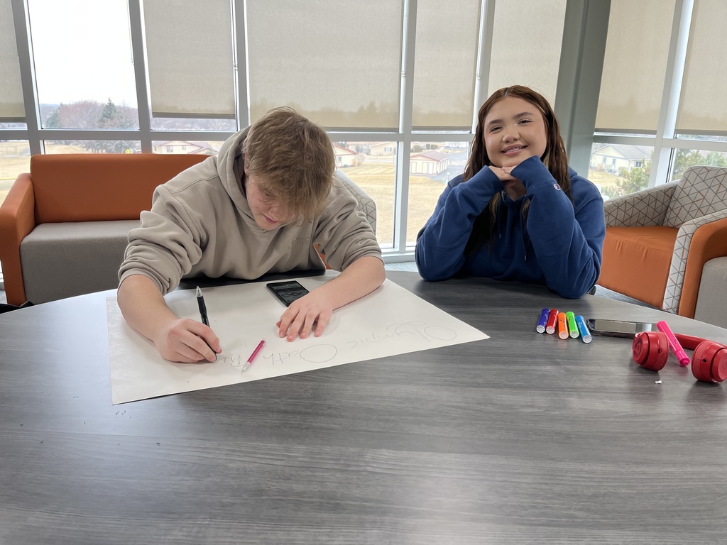 Student making poster another student sitting next to the students smiling