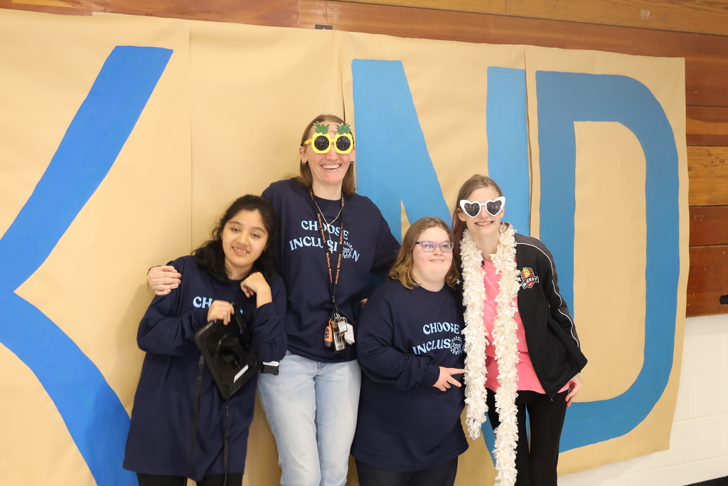 Four students standing as the I in kind, three of them wearing choose inclusion shirts two of them wearing sunglasses 