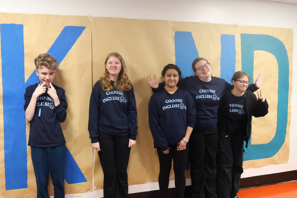 Students standing as the I in kind. Five of them in Choose Inclusion shirts 
