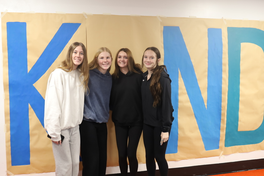 Four students standing as the I in kind