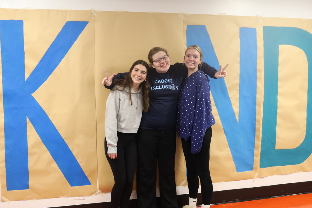 Three students standing as the I in kind 