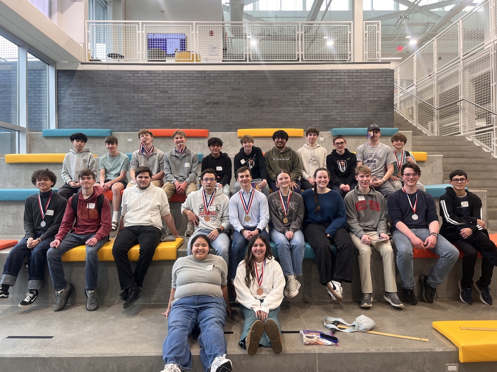 Group photo of all 25 students sitting. Some have meadals