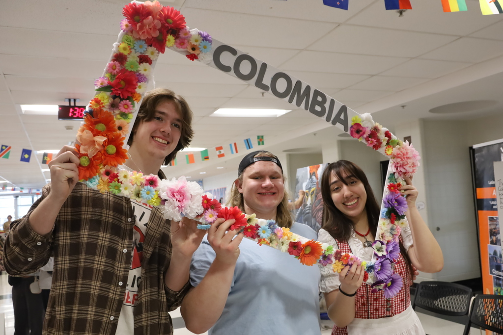 Students posing in a a Columbia frame with flowers on the frame