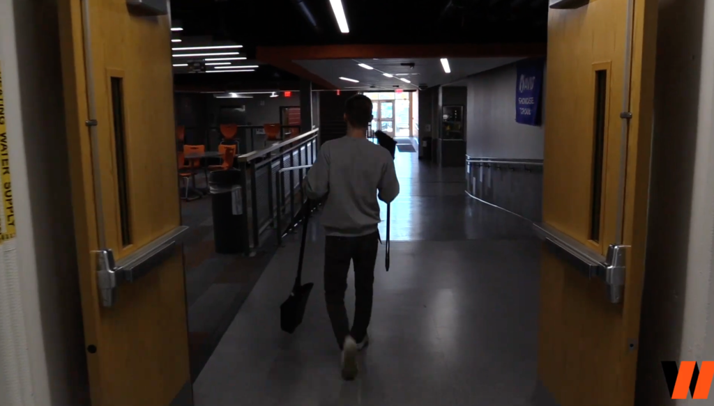 Custodian walking with broom and pan