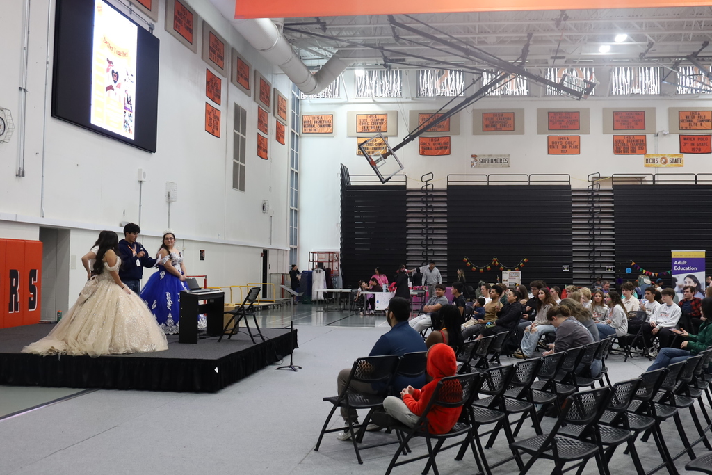 Audience in front of quincenra dresses performers on stage