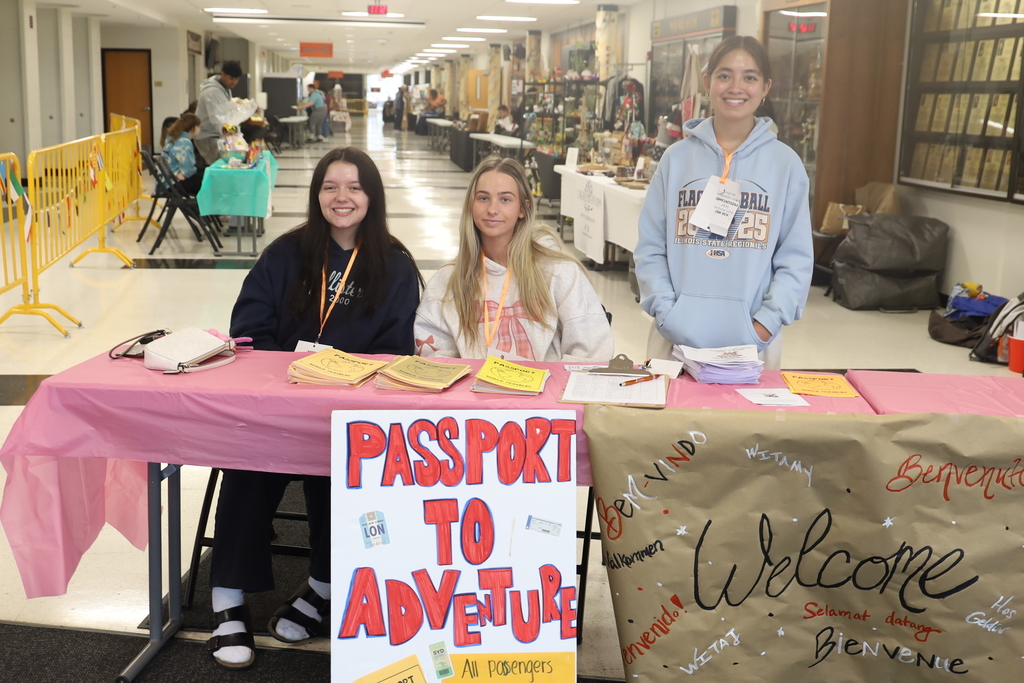 Student at table  when you walk in with welcome sign in different languages and passport to adventure sign