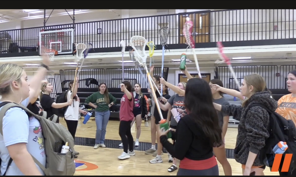 girls lacrosse holding up their nets