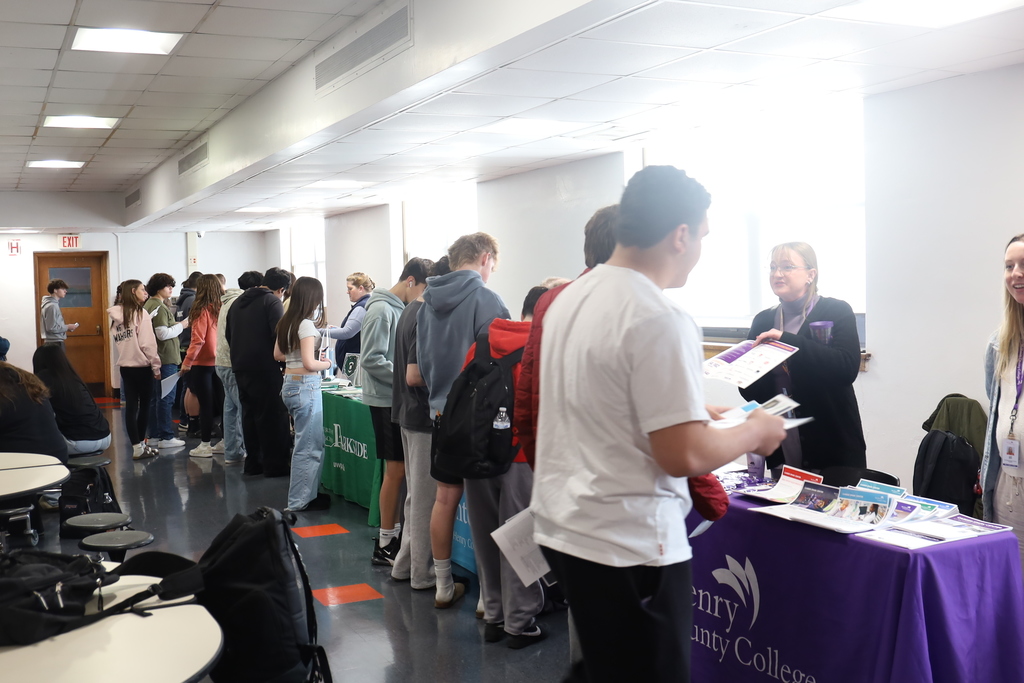 A row of students talking to a row of college representatives