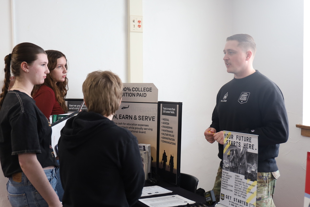 Three students talking to a representative from the army 