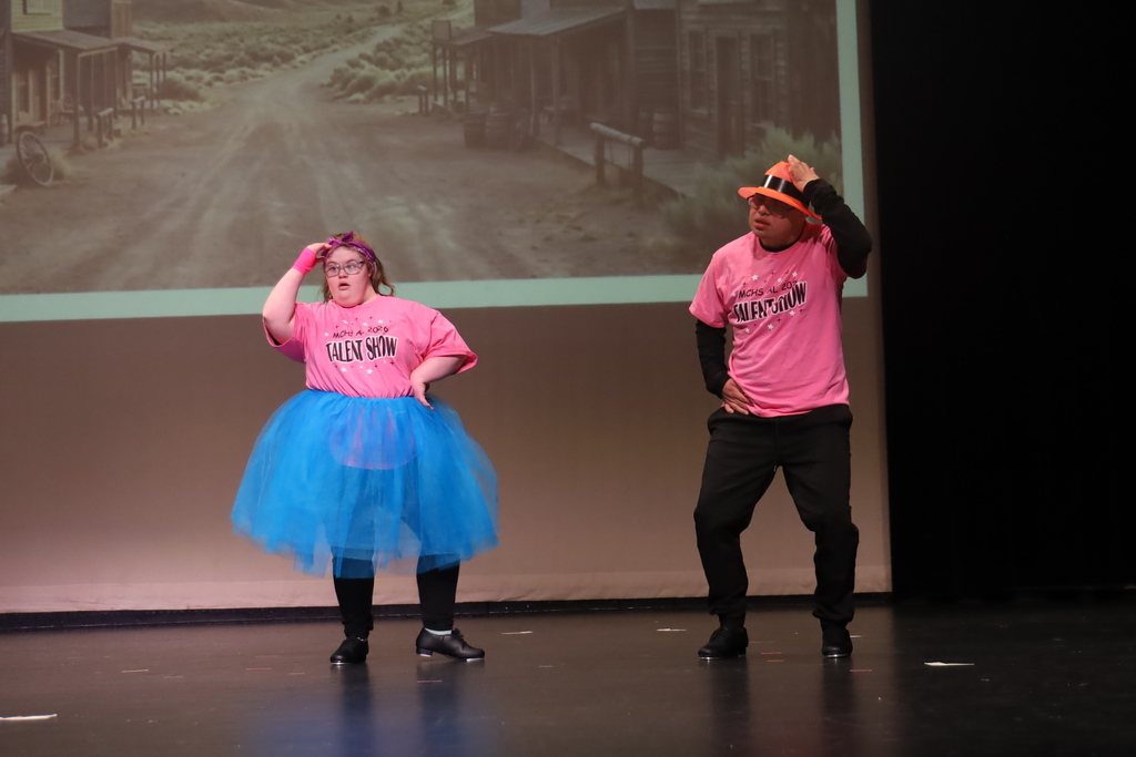 Two students dancing one has a tutu, the other orange top hat