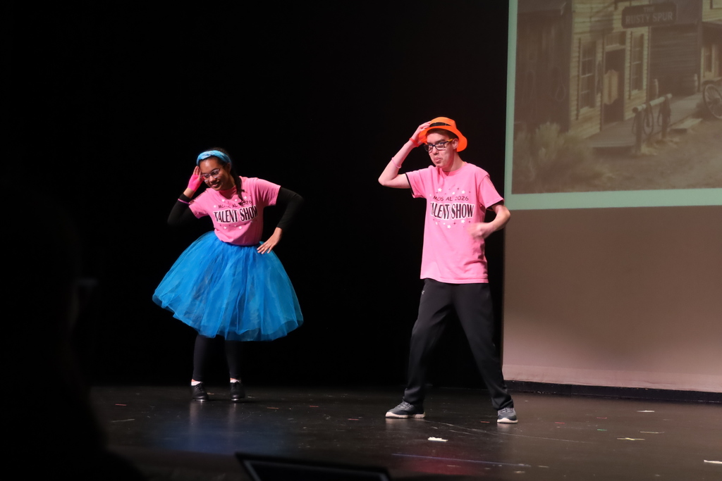 Two students dancing one has a tutu, the other orange top hat