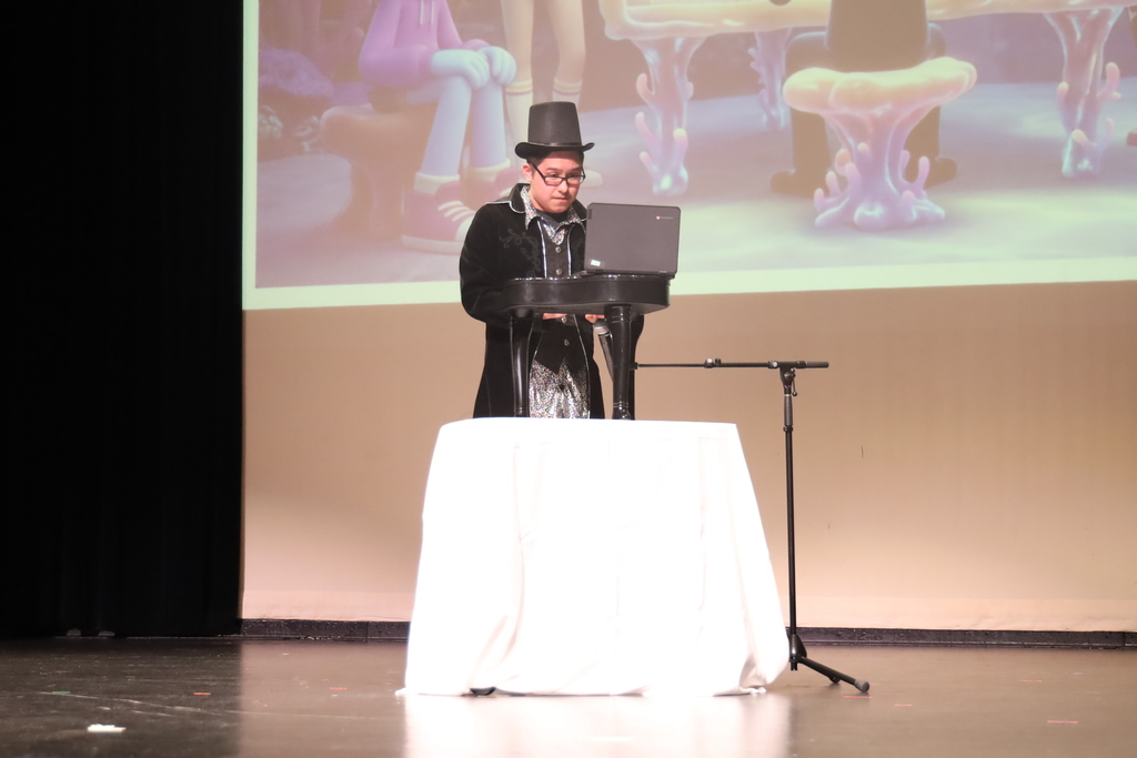 Student playing a small piano wearing a coat and a top hat