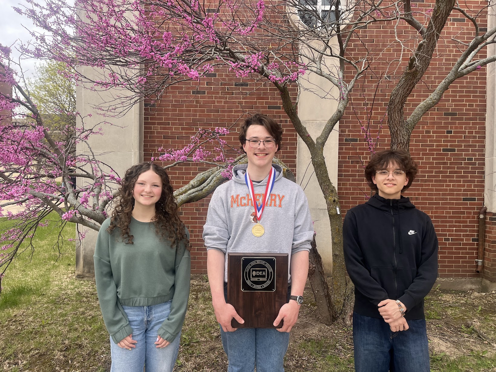 Three students on with a medal and an award