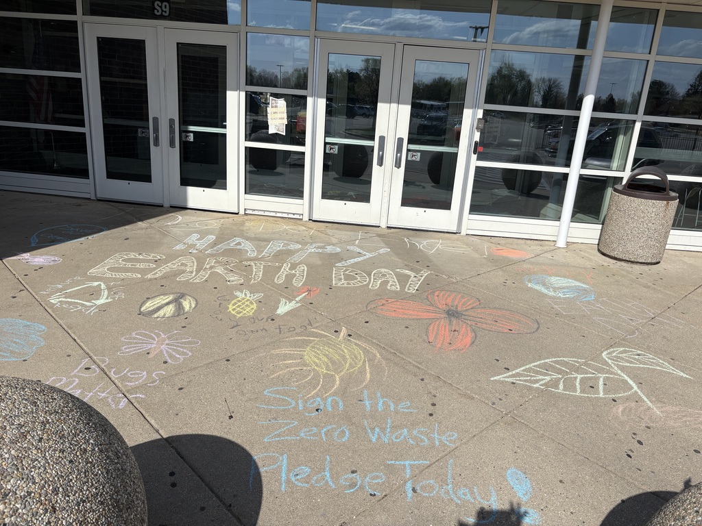 Happy earth day chalk writtenon the sidewalk of an entrance. More chalk with flowers Peace sign, butterfly with bugs matter. Sign the zero waste pledge today. 