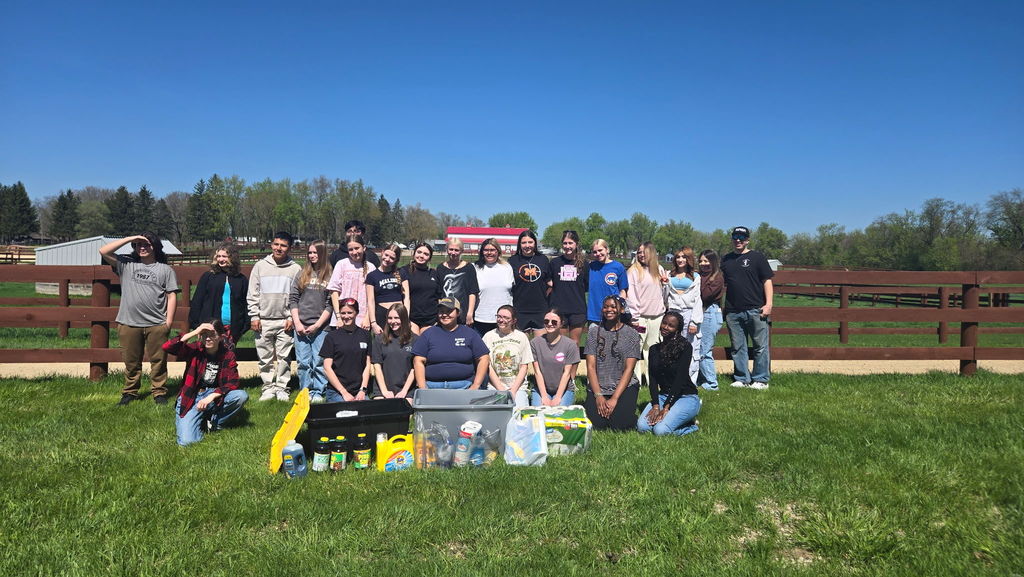 Group of students at farm with bins and supplies in front of them 
