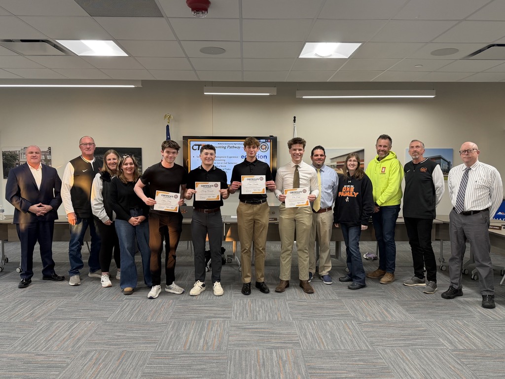 Four students holding certificates next to Nick Vlalenziano, board members and superintendent 