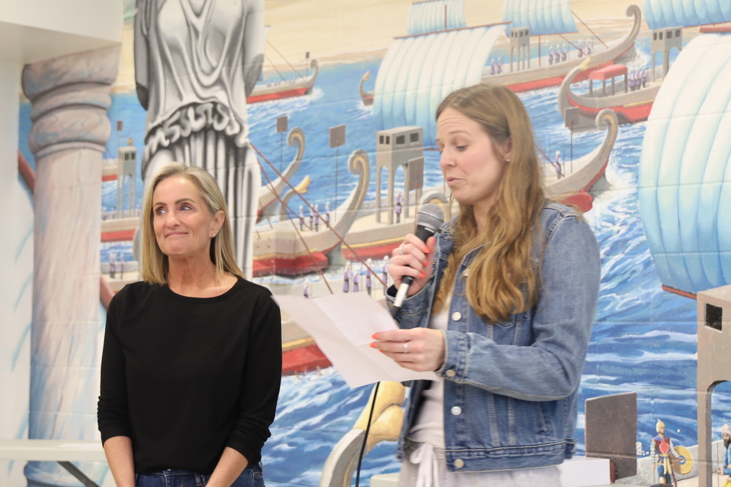 Megan Edwards reading on the microphone with Karyn Burmeister standing next to her