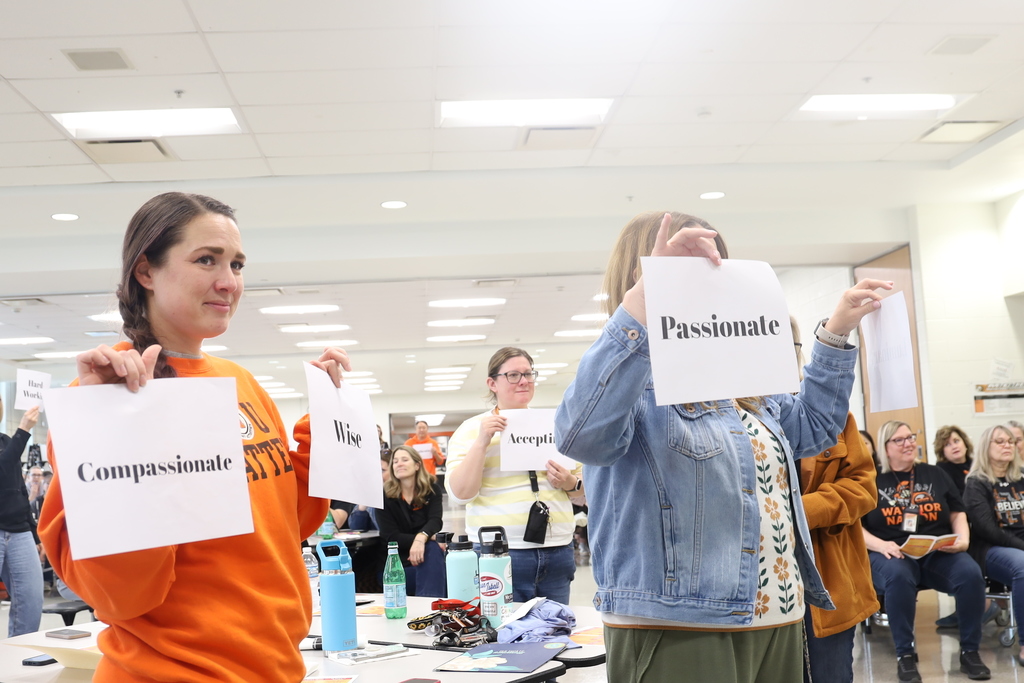 Teachers holding signs that say compassionate wise accepting and passionate