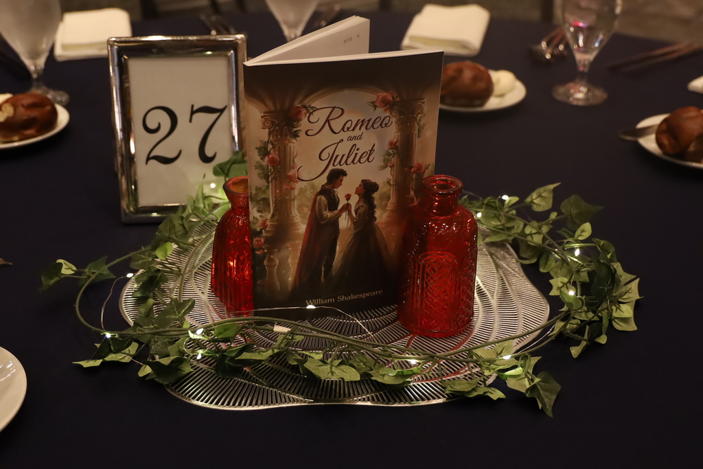 Romeo and Juliet Prom decor on table with book and vases and greenery