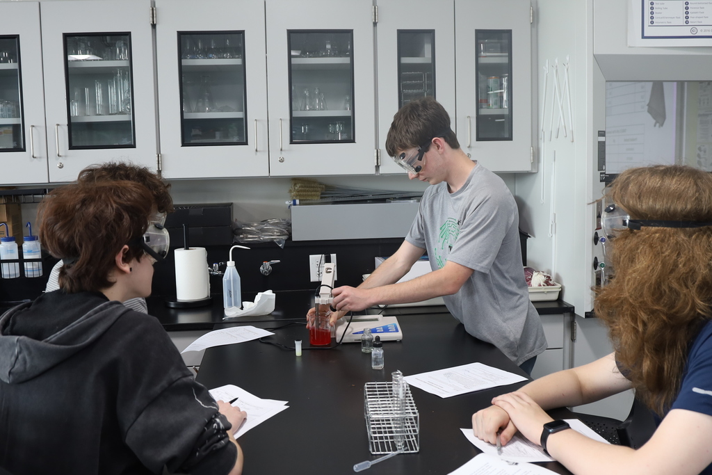Students doing a lab at a lab table with red liquid