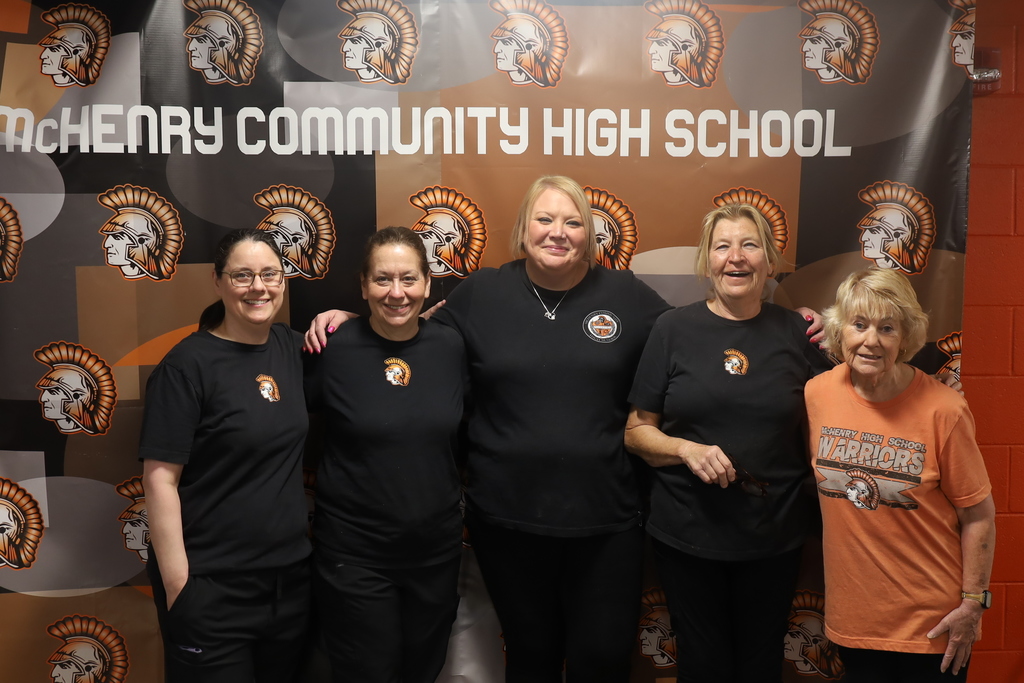Five food service staff members posing in front of McHenry Community High School banner