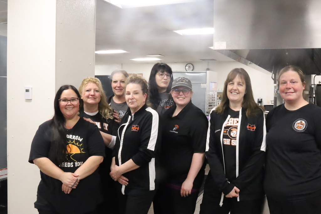 Eight food service staff member posing in kitchen