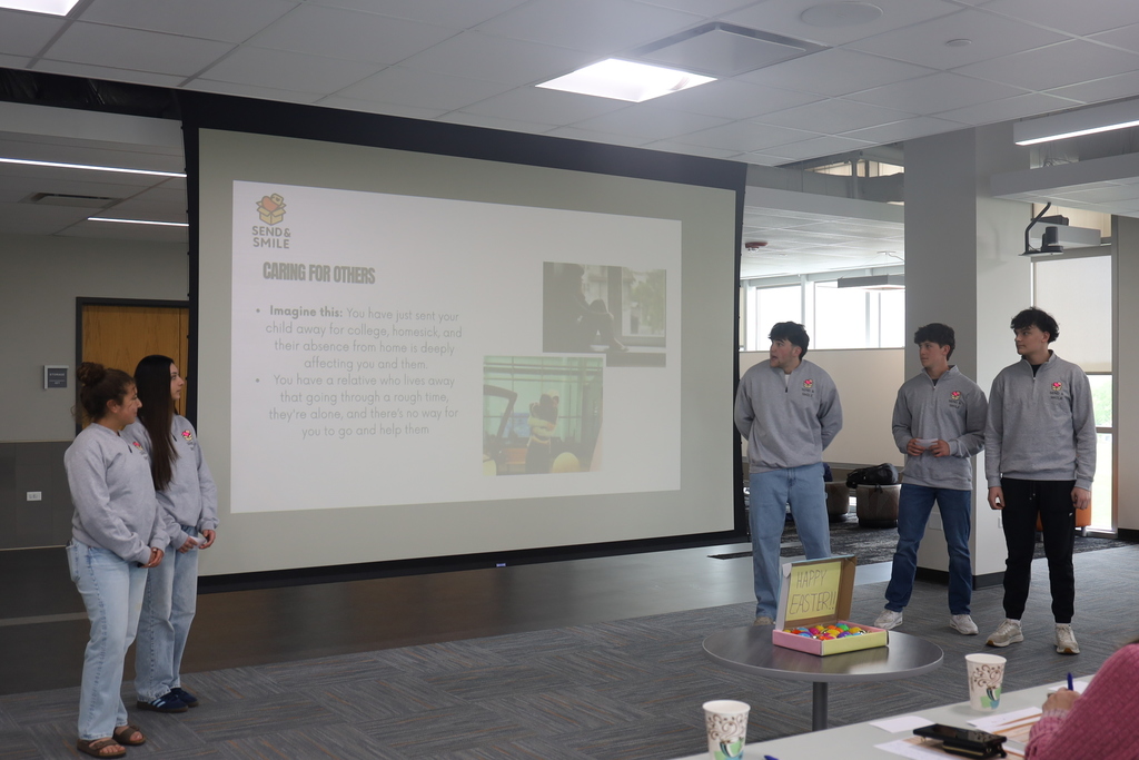 Five students presenting in front of a slide