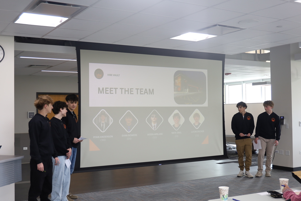 Five students presenting in front of a meet the team slide