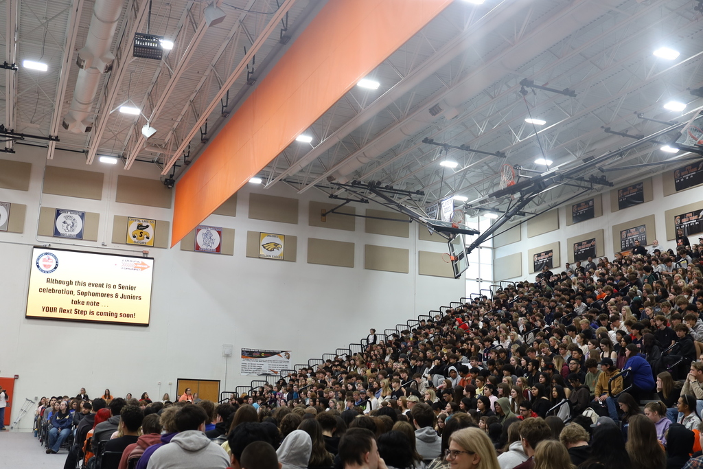 Seniors on chairs on the floor and other students in the bleachers 