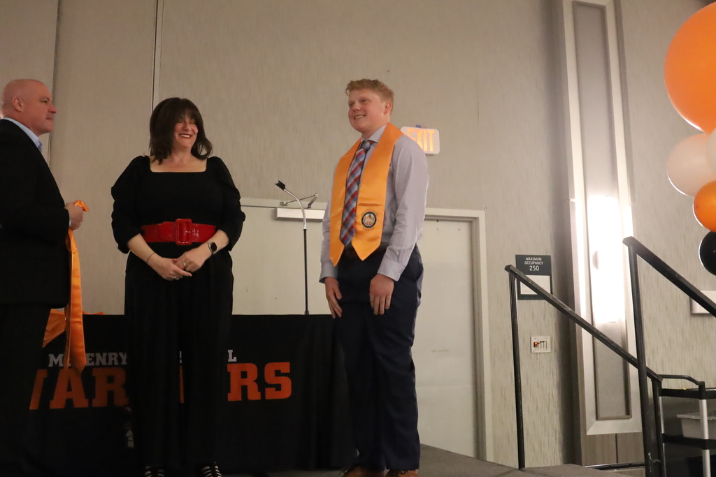Student smiling on stage with stole