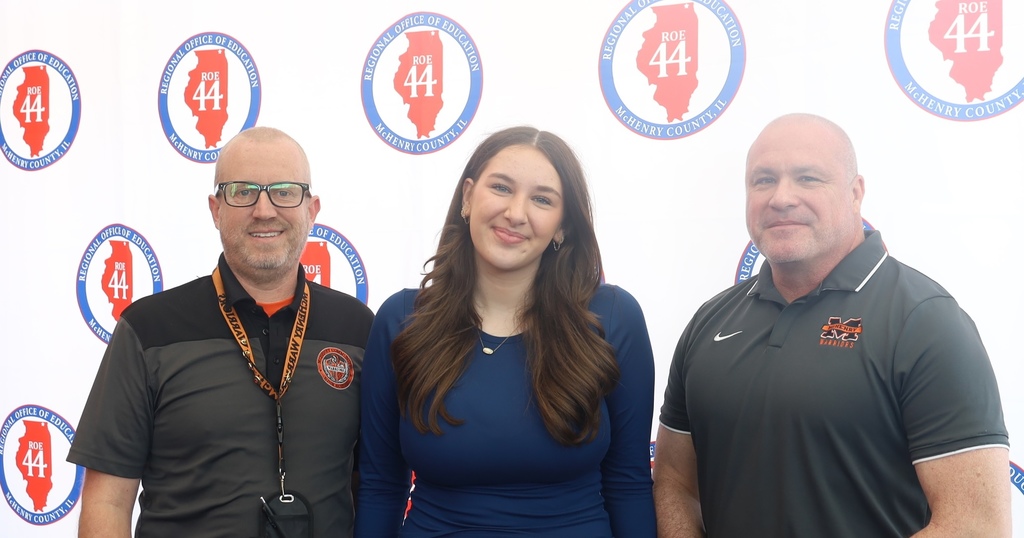 Kaitlyn with principal Eiserman and superintendent Dr. McTague in front of Regional Office of Education McHenry, IL logo backdrop 